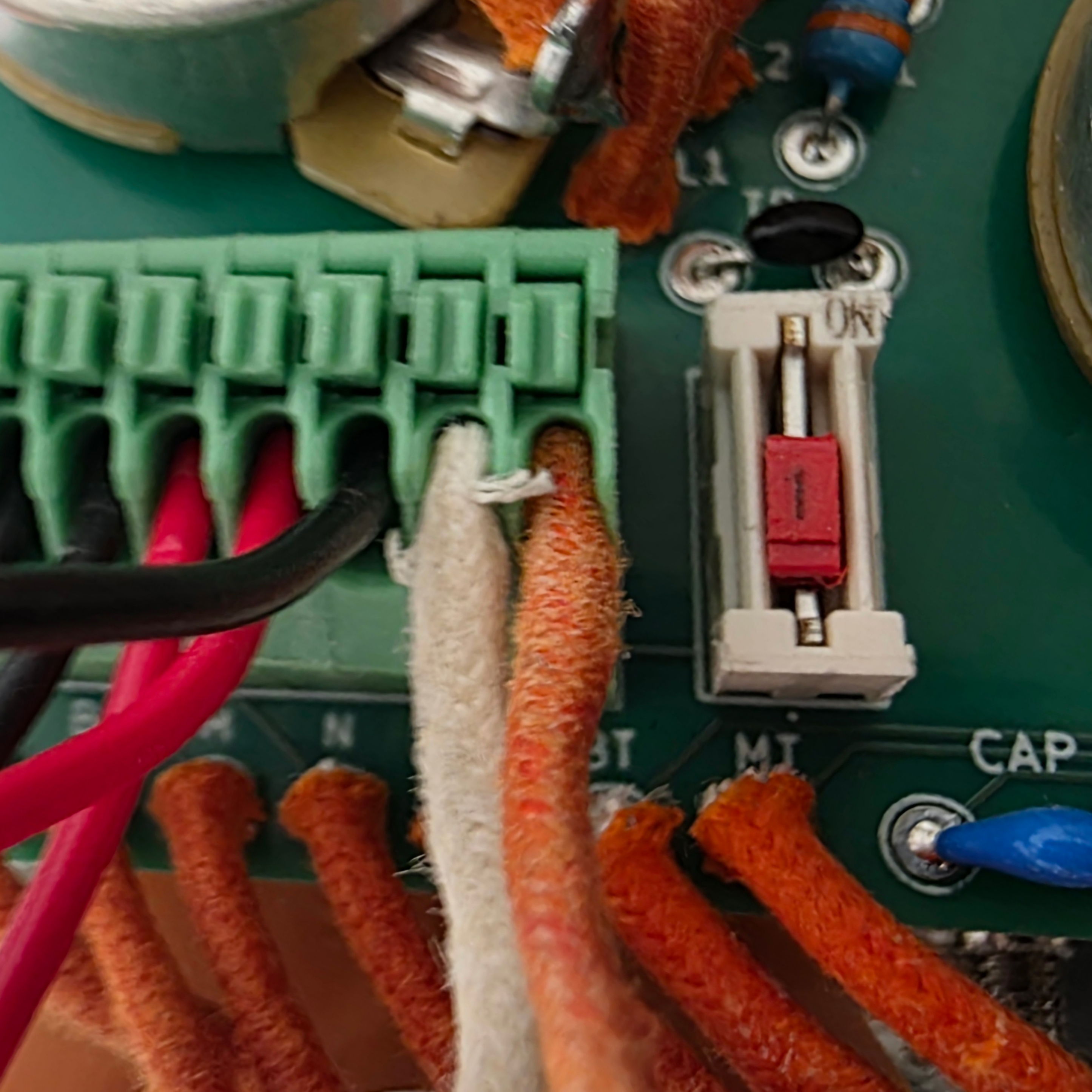 Close-up of a circuit board with wires and a fuse.