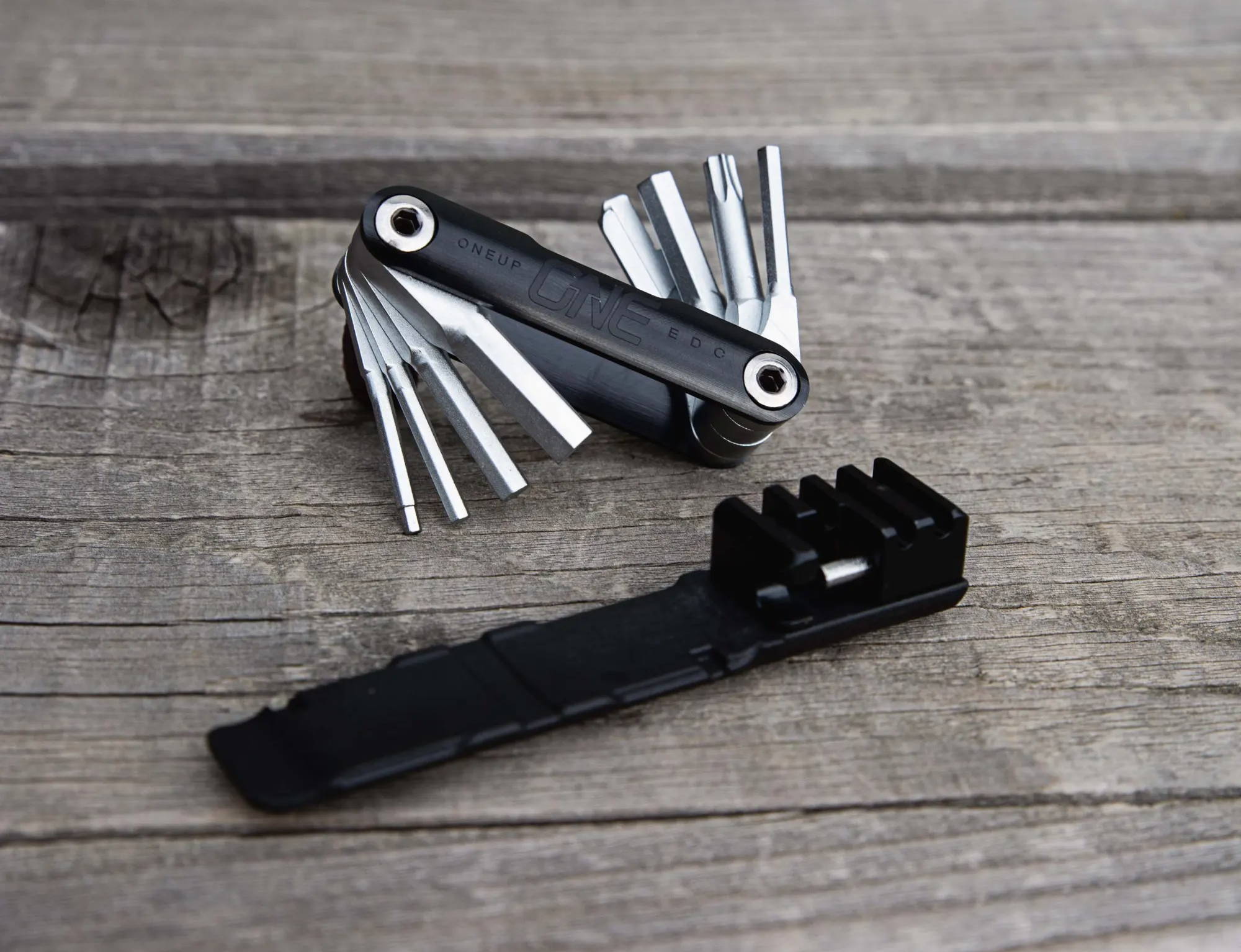 OneUp Components EDC V2 multi tool on a wood surface
