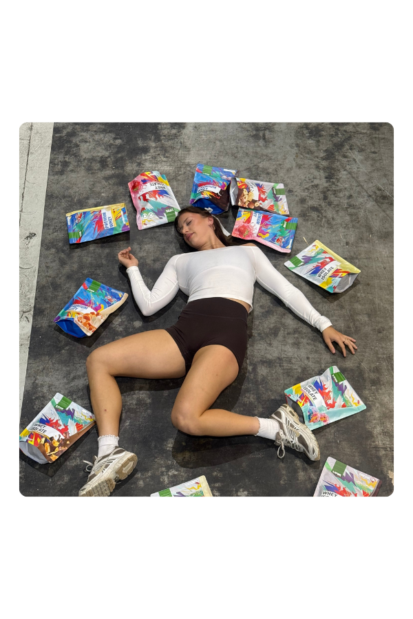 Person lying on the ground surrounded by colorful snack packages.