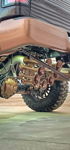 Close-up of custom bronze multi-trumpet train horn kit under rear of lifted truck with matching bronze differential cover