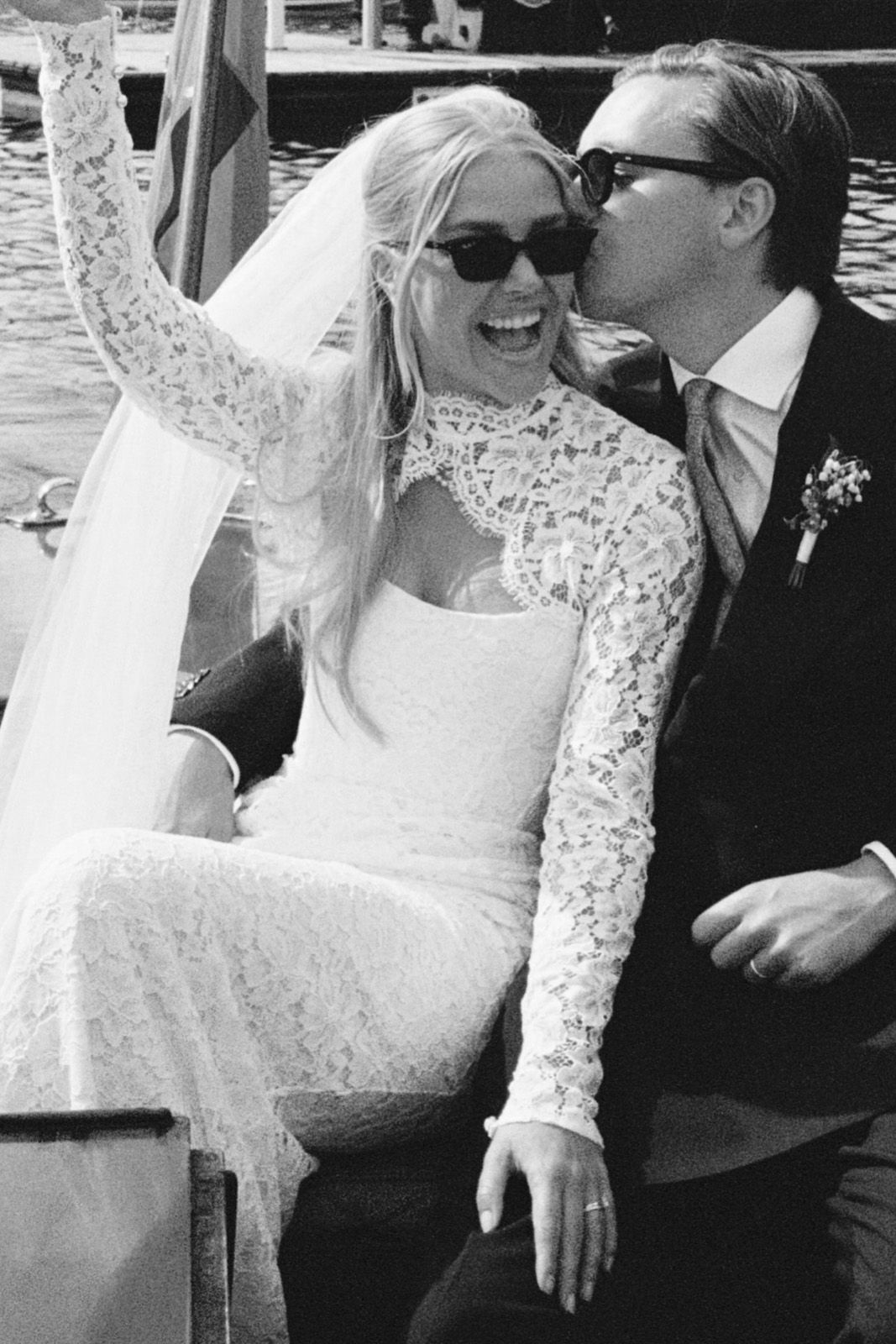 A joyful couple in wedding attire, sharing a kiss on a boat.
