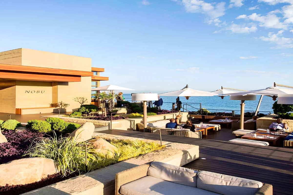 A scenic outdoor lounge area by the ocean with seating and umbrellas.