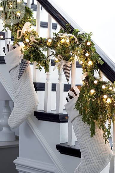 Green garland with lights on a staircase with white stockings.