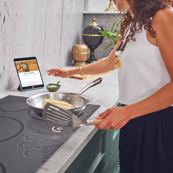woman cooking on induction cooktop using Hestan Cue