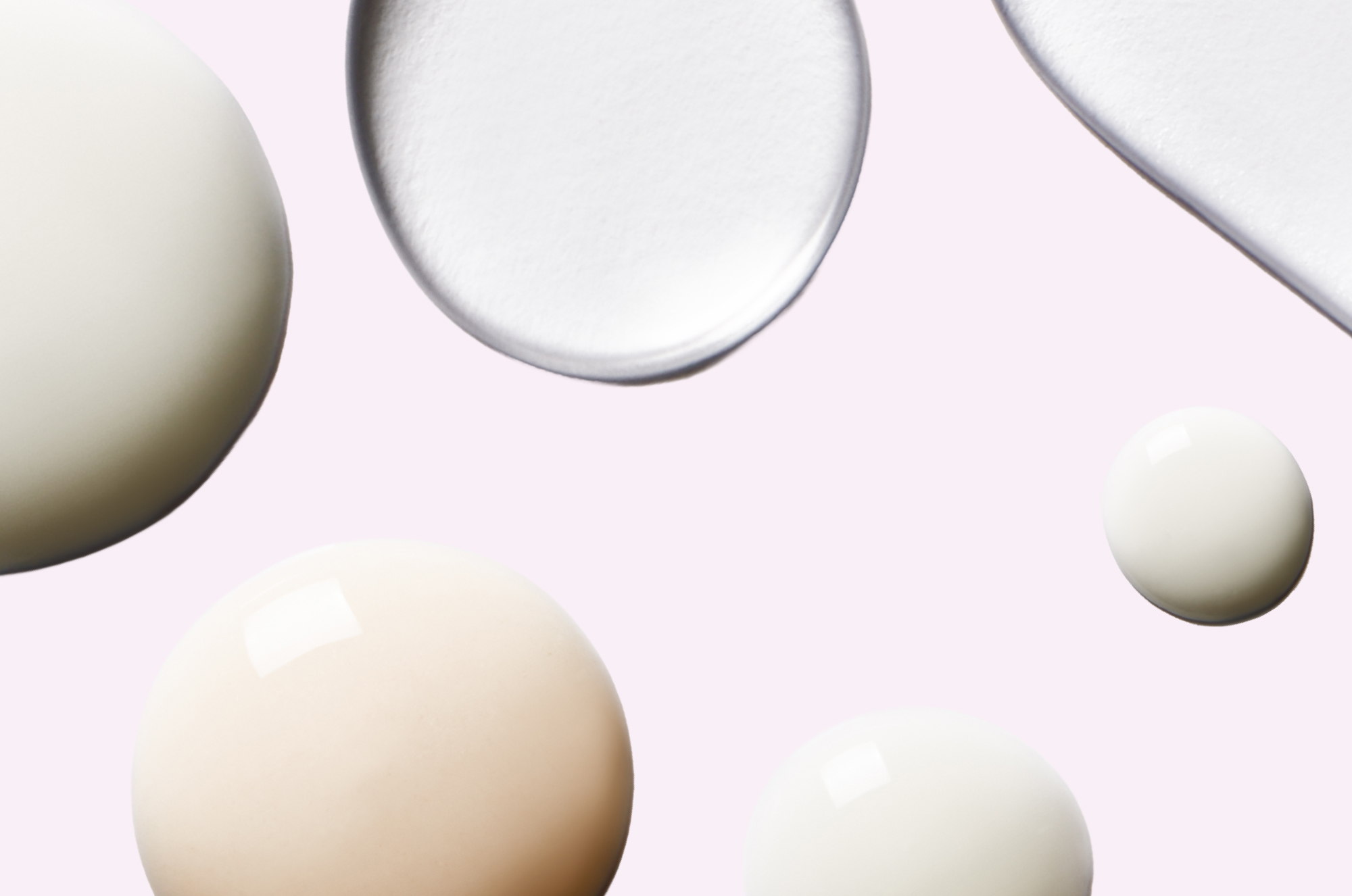 Various droplets of liquid on a soft pink background.
