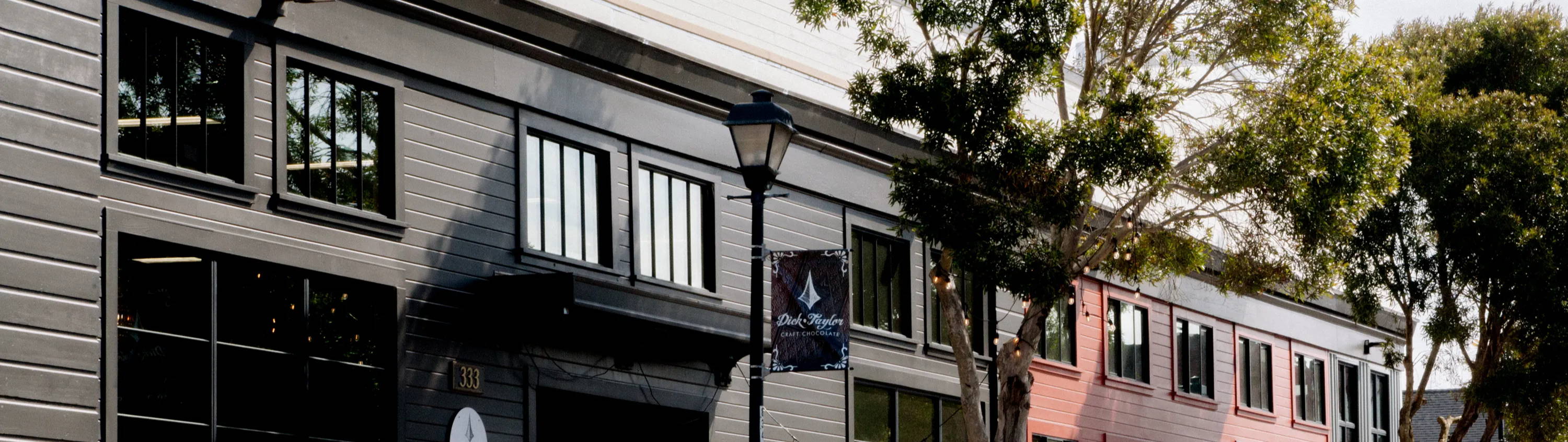 The front of Dick Taylor Craft Chocolate building with street post and trees the building