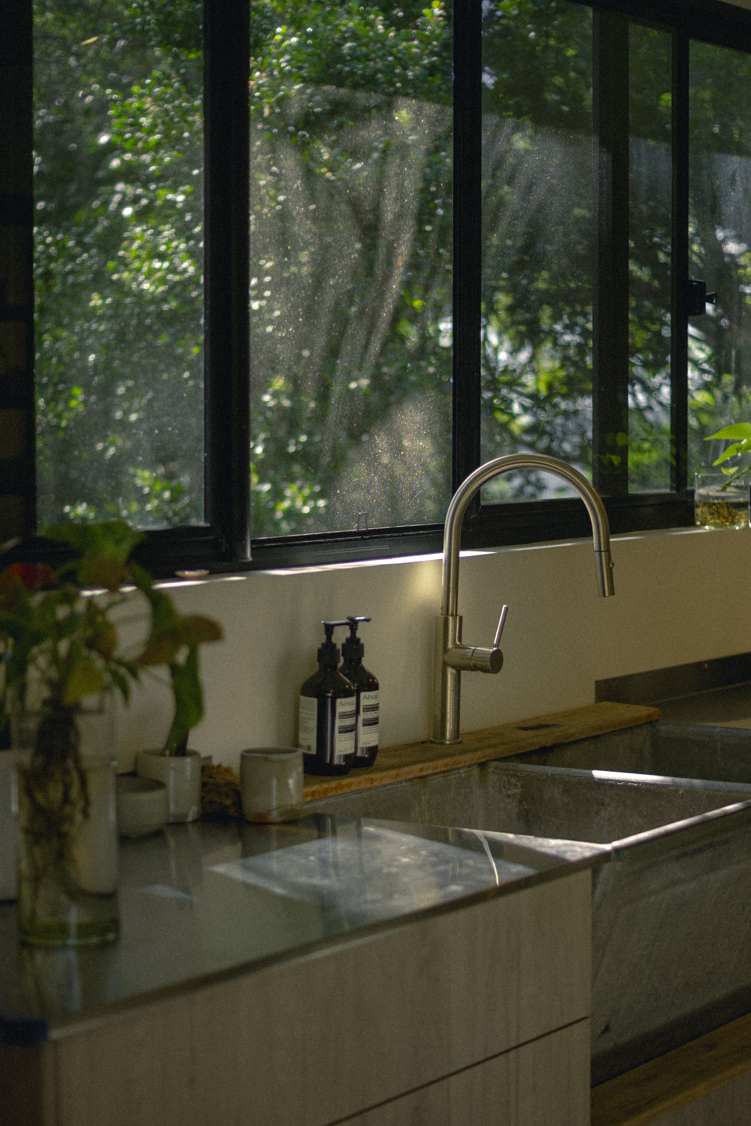 Modern kitchen interior with a view of greenery through large windows.