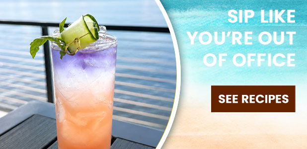 Colorful cocktail with a garnish, overlooking a body of water.