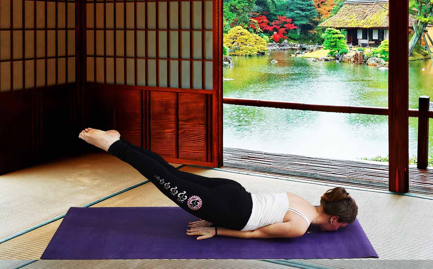 Magasin yoga strasbourg - Yogini faisant la posture de la sauterelle avec un legging yoga Asana sur un tapis de yoga toie de jute violet dans un temple bouddhiste