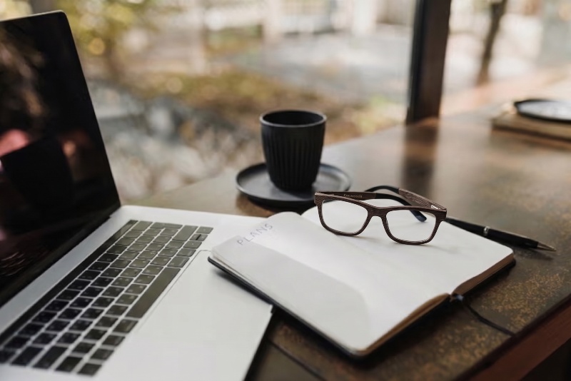 Blue light glasses placed on working desk next to laptop