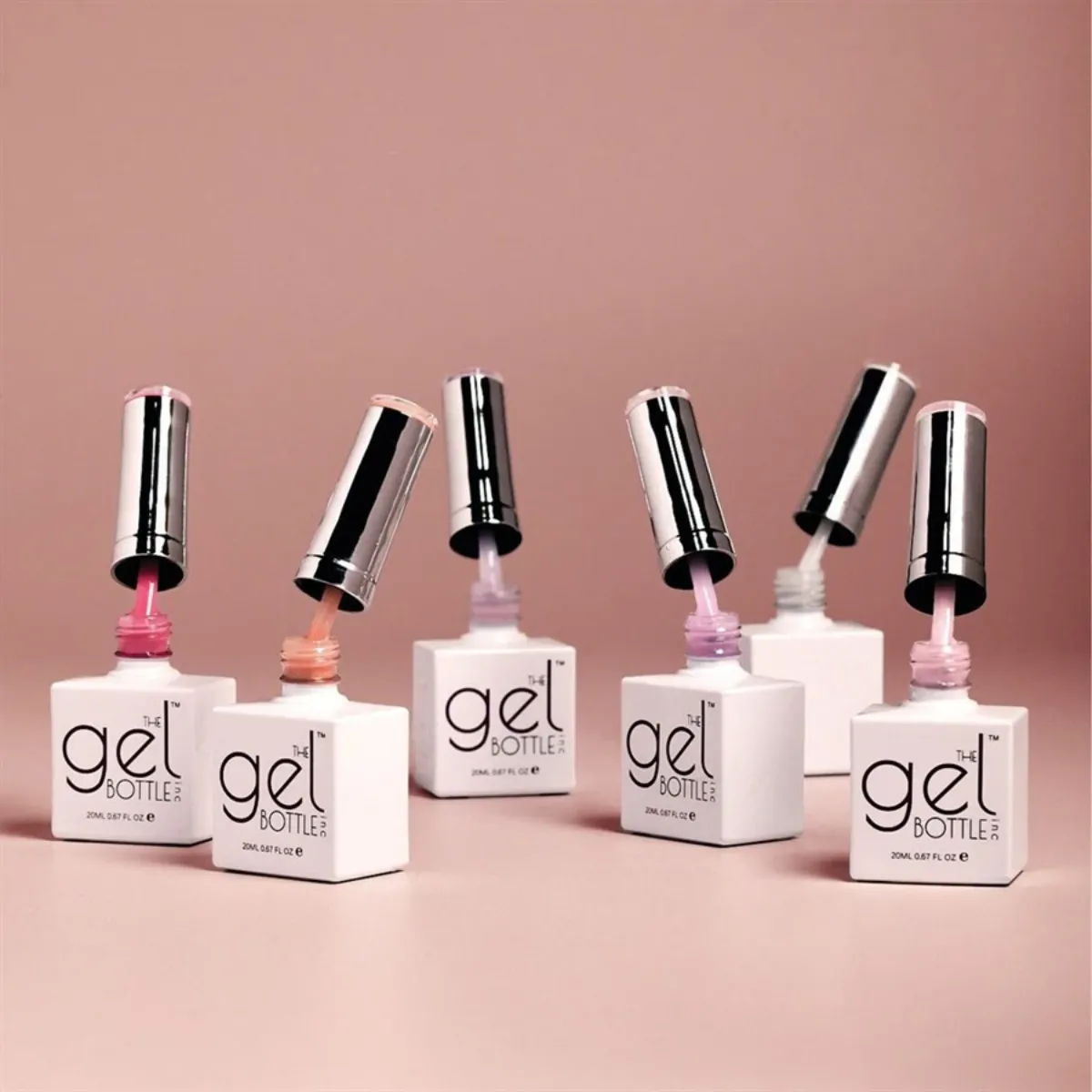 Bottles of The GelBottle Inc gel nail polish on a pink background.