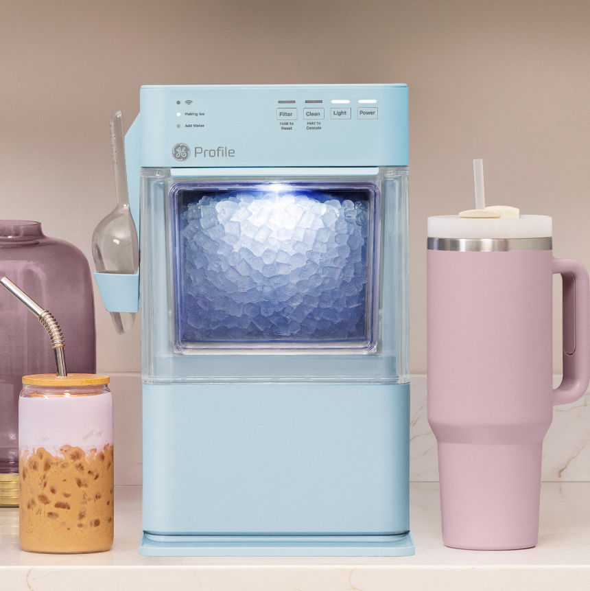 A blue beverage maker next to colorful cups on a countertop.