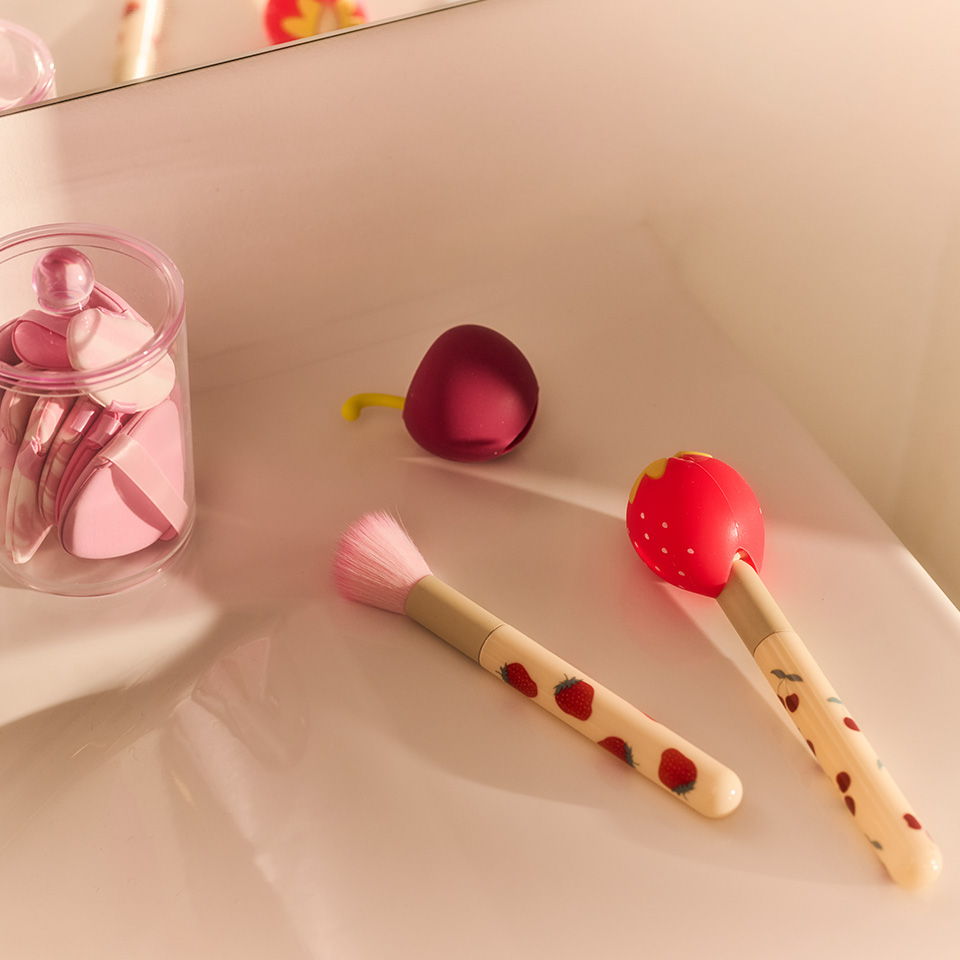 Colorful makeup brushes arranged on a surface with a container of brushes.
