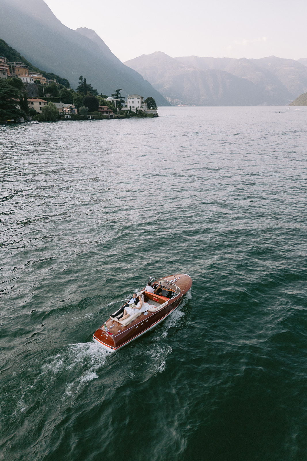 A boat gliding over calm water with mountains in the background.