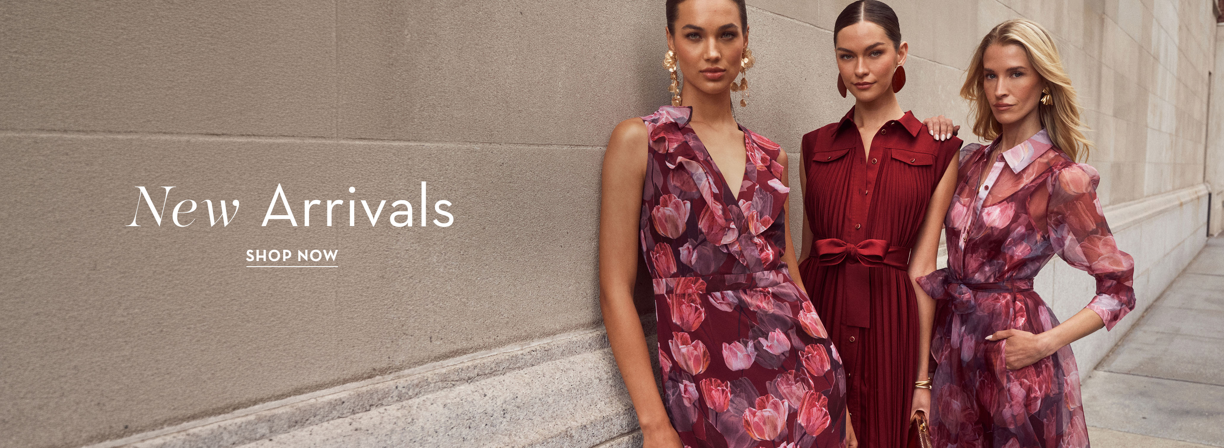 Three women modeling new floral dresses against a neutral backdrop.