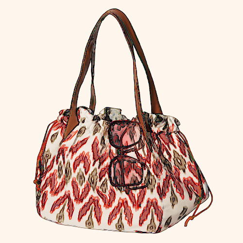 A patterned handbag with brown straps and sunglasses resting on top.