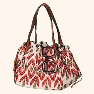 A patterned handbag with brown straps and sunglasses resting on top.