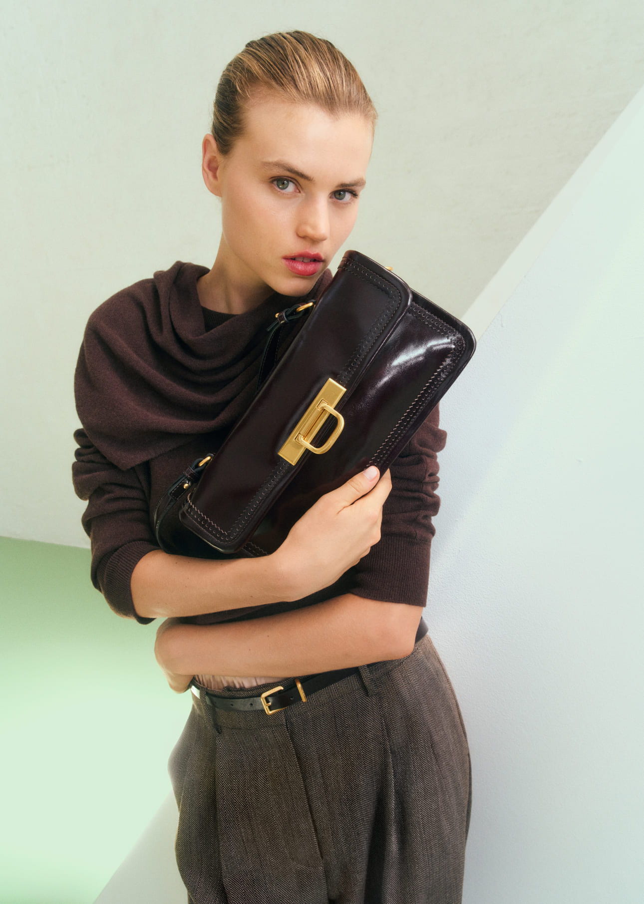 Woman holding a stylish black clutch, wearing a sophisticated outfit.