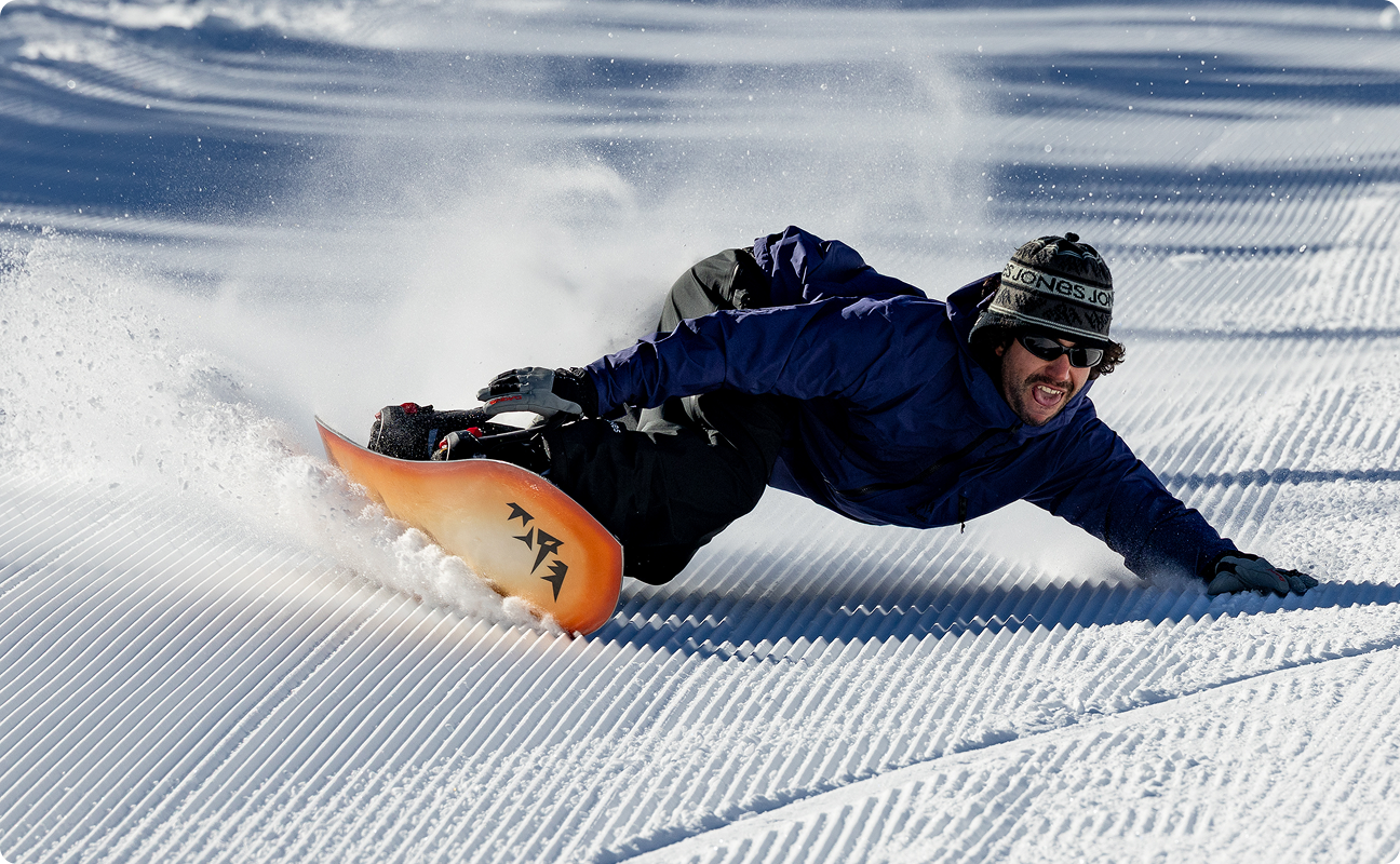 Person snowboarding down a slope, creating a spray of snow.