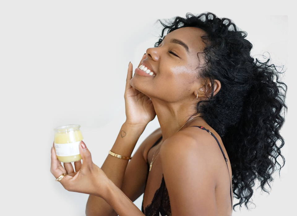 Woman enjoying applying LOLI Beauty's all natural moisturizer on her face