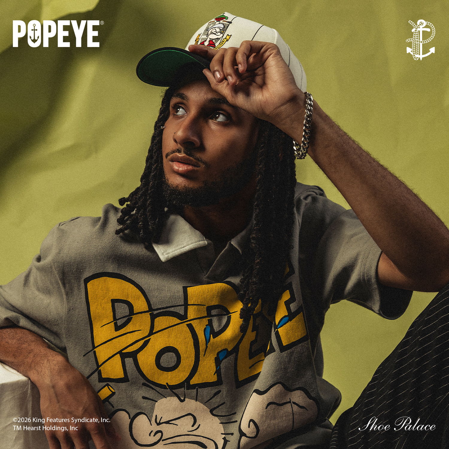 Person wearing a Popeye shirt, posing against a green background.