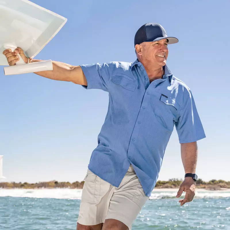 Man leaning off side of boat wearing Globe Trotter Short Sleeve Shirt by Weekender.
