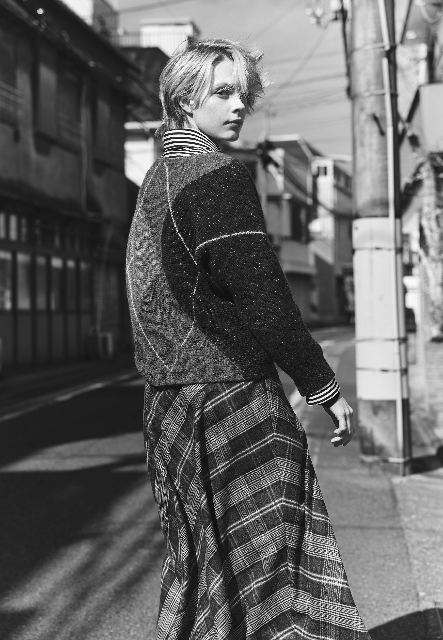 Person in a stylish outfit walking down an empty street in black and white.