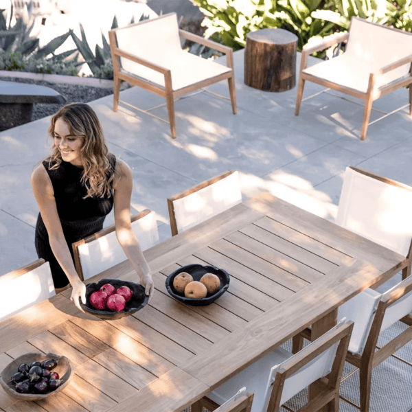 Teak outdoor dining table and chairs arranged for entertaining on a shaded residential patio