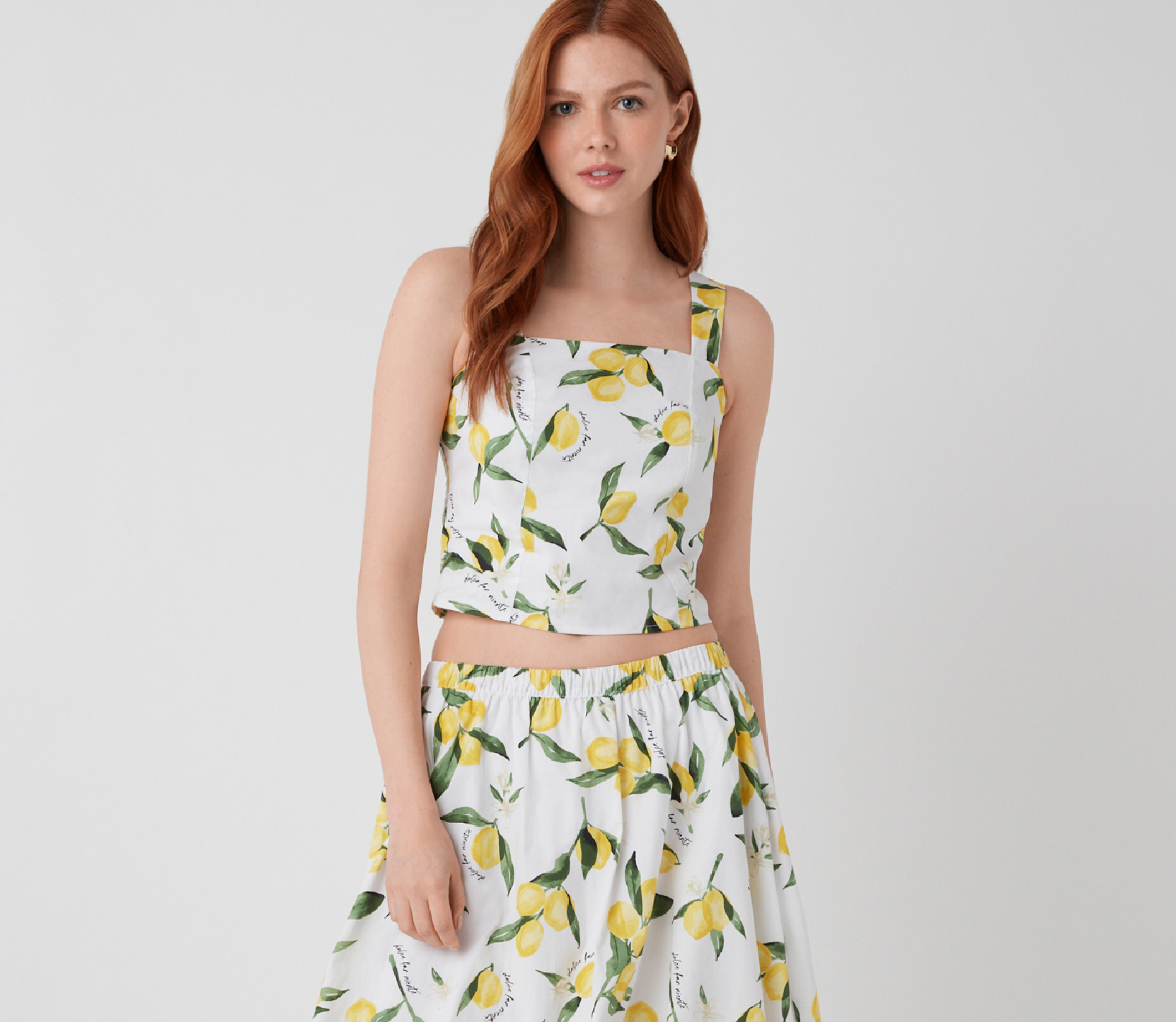 A woman wearing a floral crop top and matching skirt.
