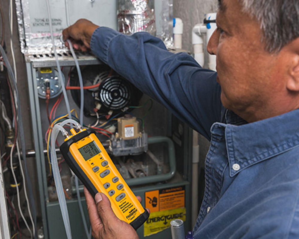 Technician using a multimeter on a heating system.