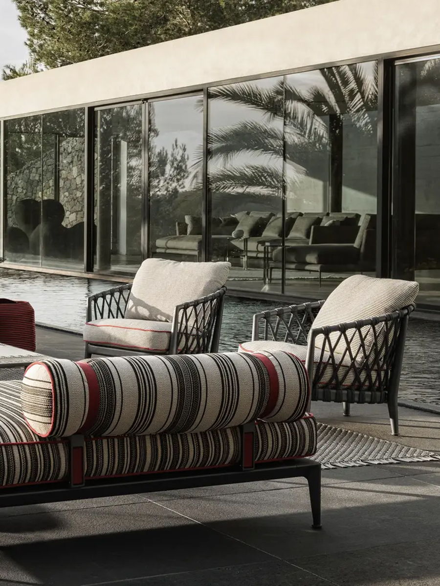 Stylish outdoor seating by a pool with modern architecture and reflections.