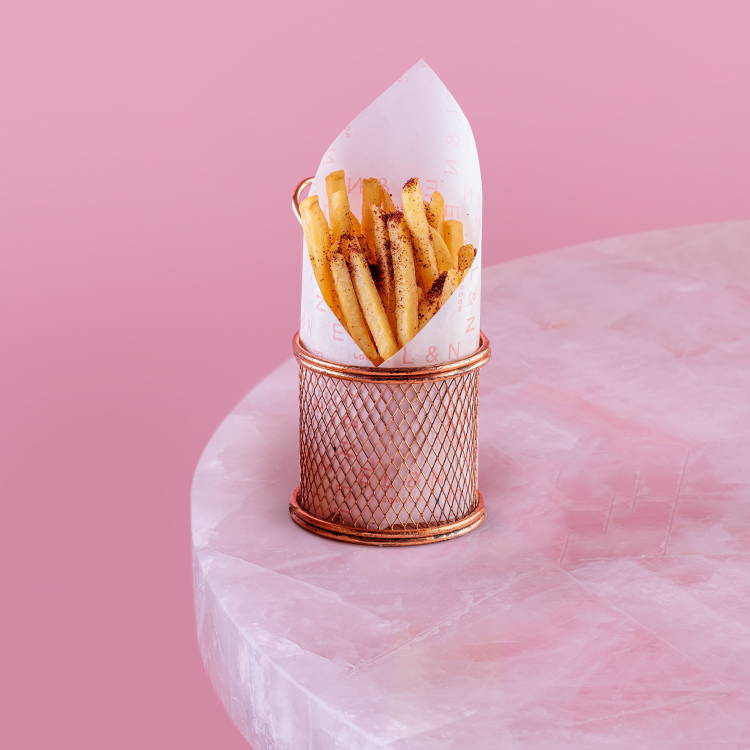 Skinny fries on a pink background in a basket