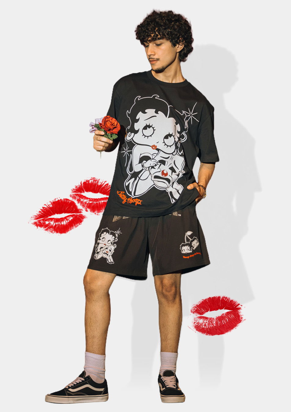 Person wearing graphic t-shirt and shorts, holding a flower with playful graphics.