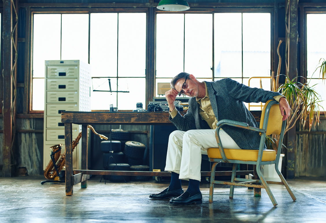 Man sitting in a chair, looking thoughtful in an office setting.