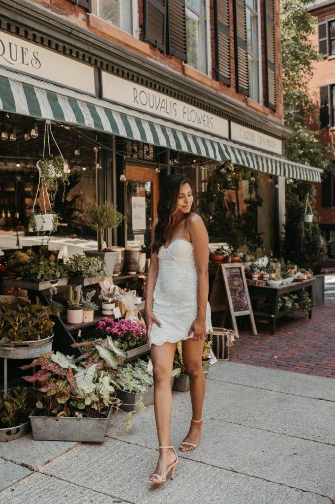 Bride wearing short white strapless lace dress outside a florist