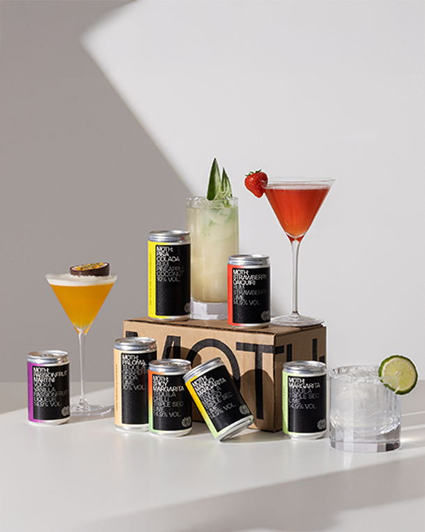 Assorted cocktails and canned beverages displayed on a white table.