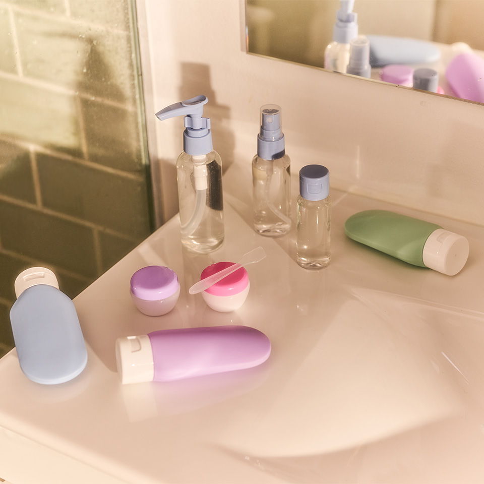 Assorted cosmetic and toiletry bottles on a bathroom countertop.