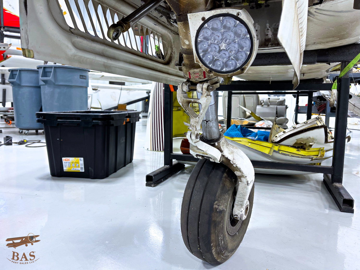 Close-up of an aircraft wheel and pressure gauge in a workshop.