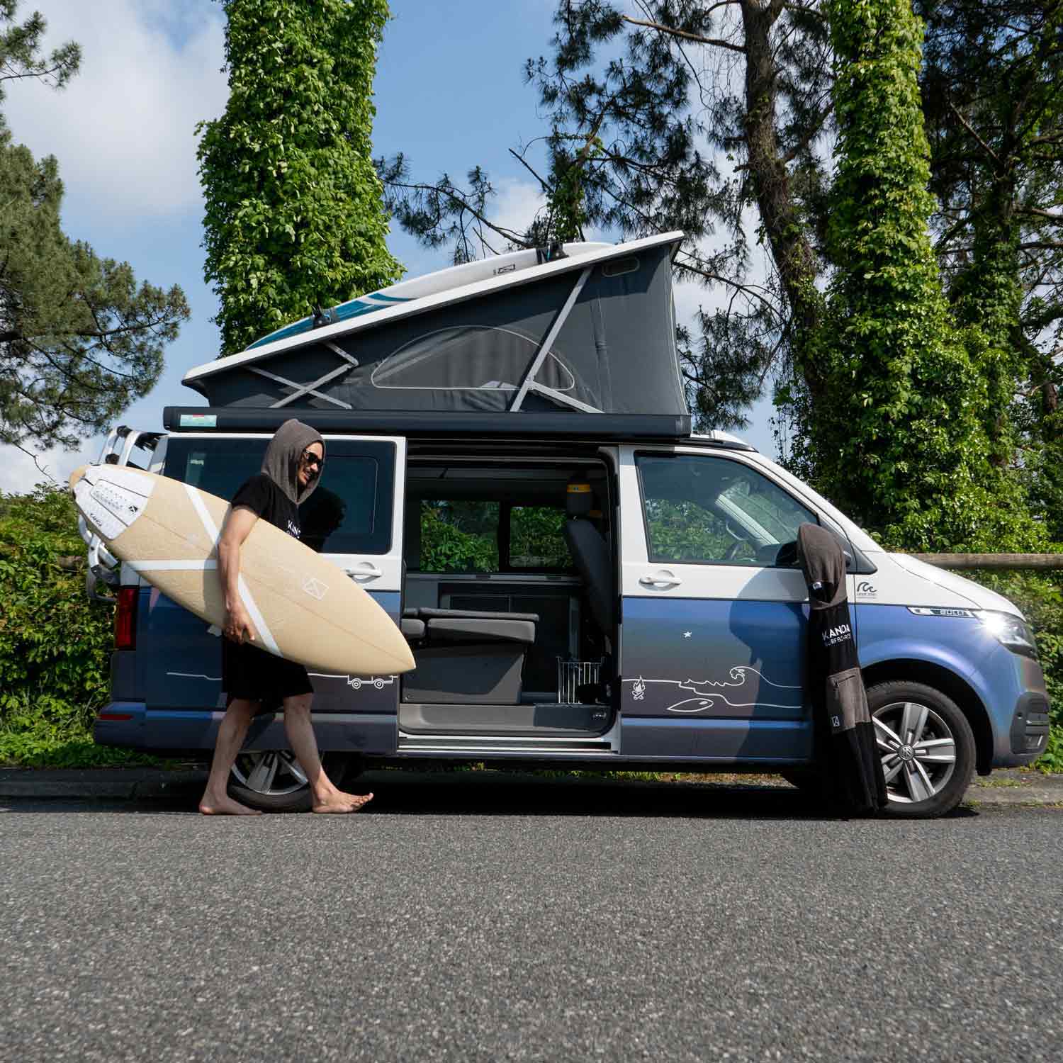 Seti Burling with our sustainable Polyola Surfboard in front of a Roadsurfer Van