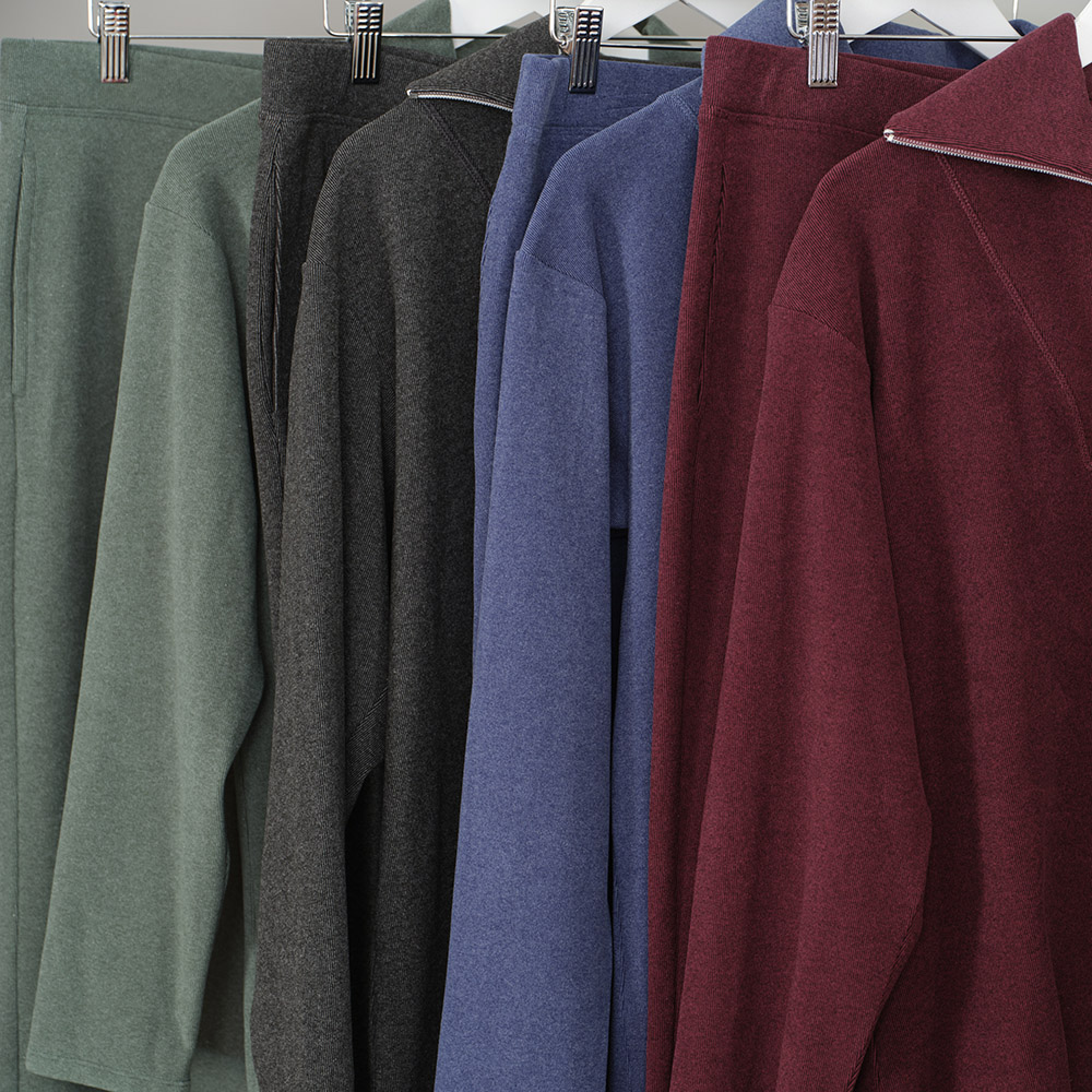 Various sweaters in different colors hanging on hangers.