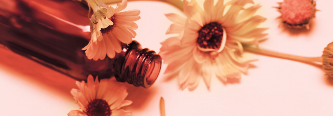 Brown bottle surrounded by yellow flowers on a pink background.