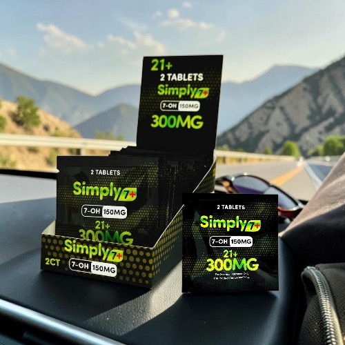 Various packages of Simply CBD tablets displayed outdoors with mountains in the background.