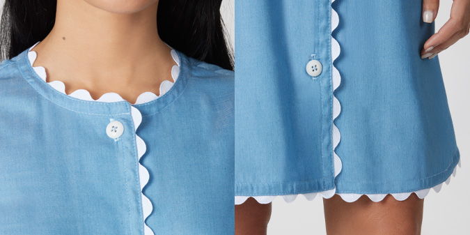 Close-up of a blue dress with scalloped edges and buttons.