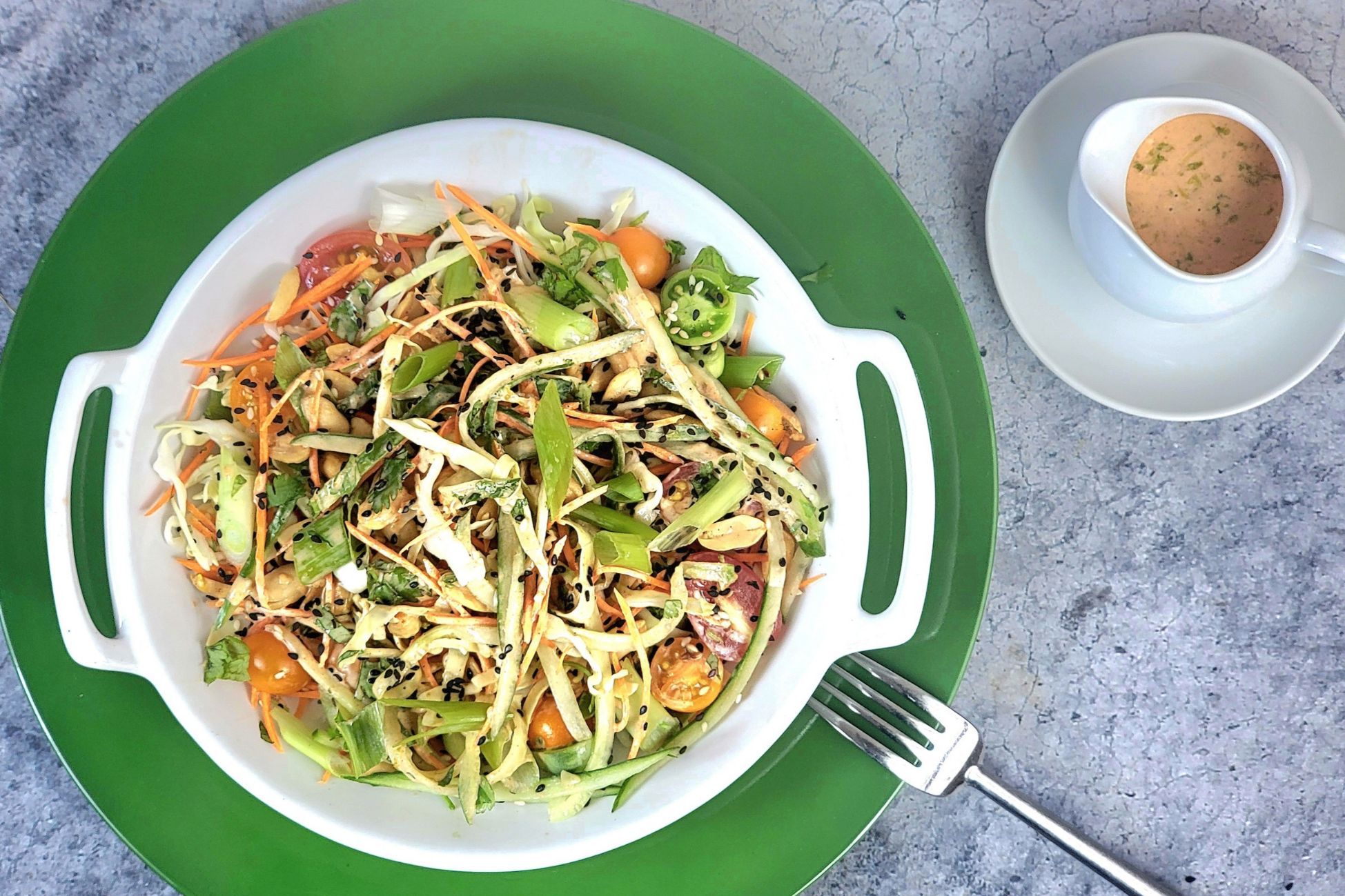 A colorful salad in a white bowl, with a cup of coffee beside it.