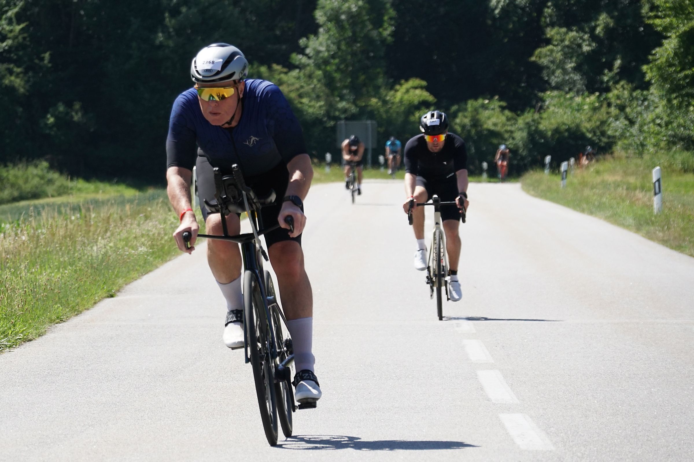 Triathleten auf dem Fahrrad in großem Abstand hintereinander auf einer Landstraße