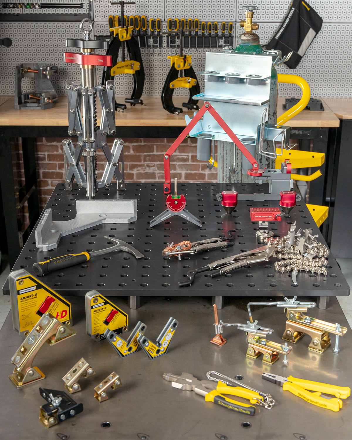 Assorted clamps and tools arranged on a workbench with a pegboard background.