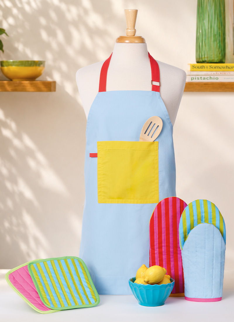 Colorful kitchen apron with mitts and dishcloths, featuring lemons in a bowl.