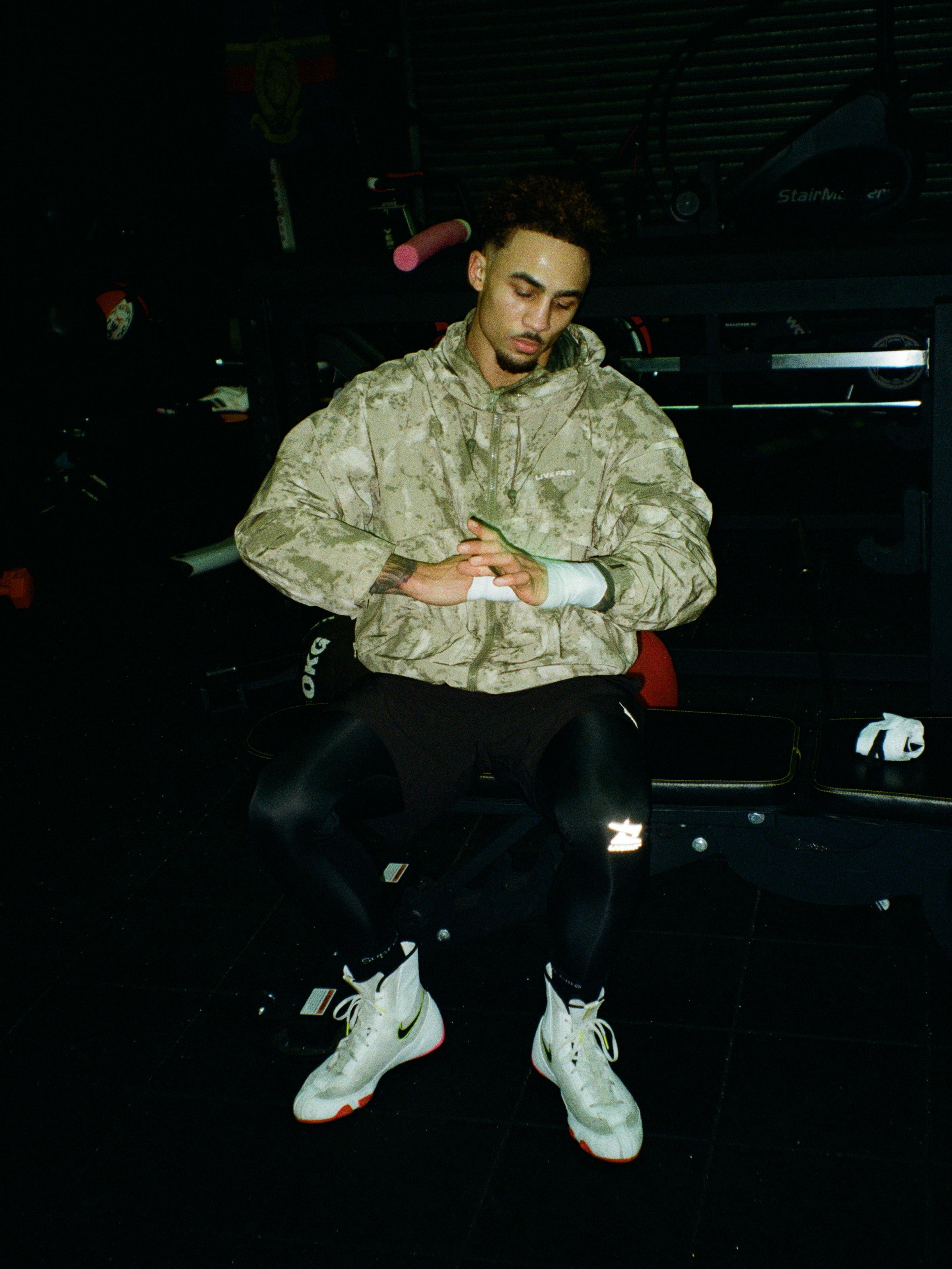 Person in camouflage jacket preparing for workout in a gym setting.