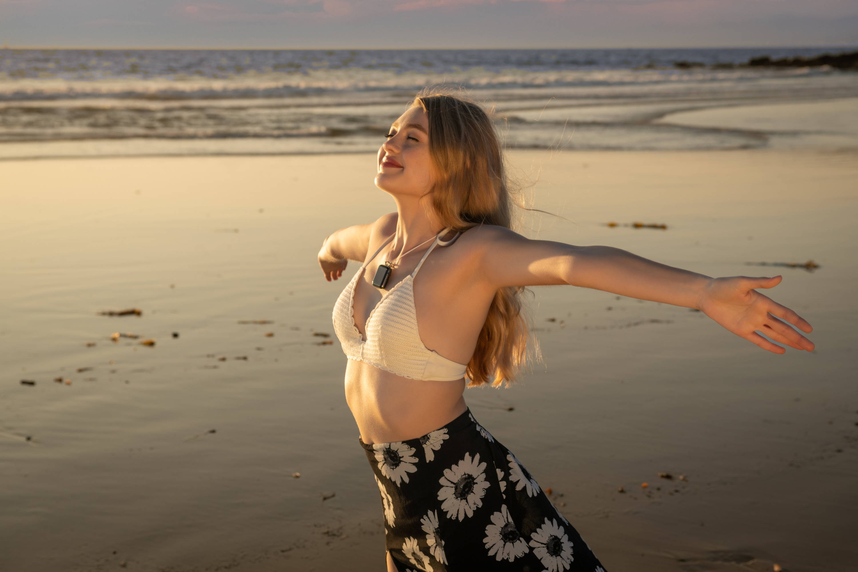 Happy woman taking a deep breath with arms open on beach
