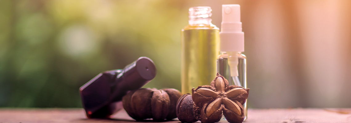 Bottles of essential oils with nuts on a wooden surface.